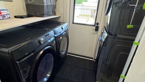 Een kleine wasruimte met een wasmachine, droger en een klein aanrecht.