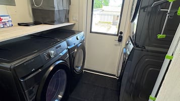 A compact laundry room with a washing machine, dryer, and a small countertop.