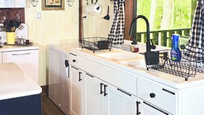 A kitchen with white cabinets, a sink, and a window with a view of greenery.