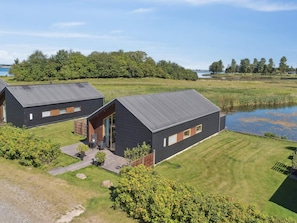 Two modern cabins with metal roofs, surrounded by a well-maintained lawn and a body of water. - 4 Star Holiday Home in Stubbekobing (Stubbekobing)