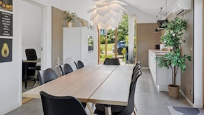 A modern kitchen with a dining area, featuring a large table, chairs, and a unique ceiling light fixture. - 4 Star Holiday Home in Stubbekobing (Stubbekobing)