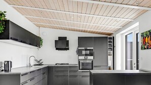 A modern kitchen with dark cabinetry, a gas stove, a microwave, and a built-in oven. - "Bilal" - 1.8km from the sea by Interhome (Rømø)