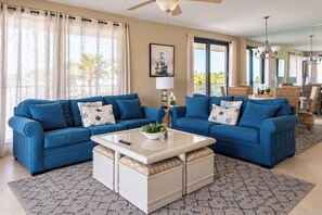 Un salon avec deux canapés bleus, une table basse blanche et un tapis à motifs.