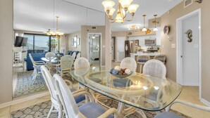 Un espace repas moderne avec une table en verre, des chaises en osier et un lustre.