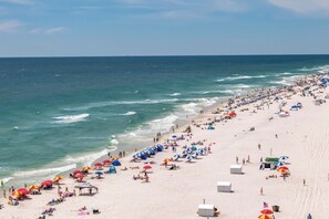 A beach with umbrellas, people, and beach huts. - 2nd Floor Corner Unit Condo with 3BR, 2BA in beautiful Orange Beach! (Orange Beach)
