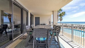 Un balcon avec une table et des chaises, une porte et une vue sur l’océan.