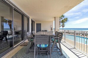 A balcony with a table and chairs, a door, and a view of the ocean. - 2nd Floor Corner Unit Condo with 3BR, 2BA in beautiful Orange Beach! (Orange Beach)
