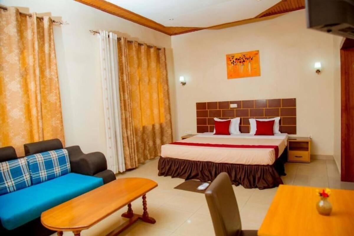 A hotel room with a bed, a sofa, a desk, and a chair.