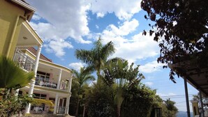 Un edificio de dos pisos con balcón, rodeado de palmeras y un patio empedrado.