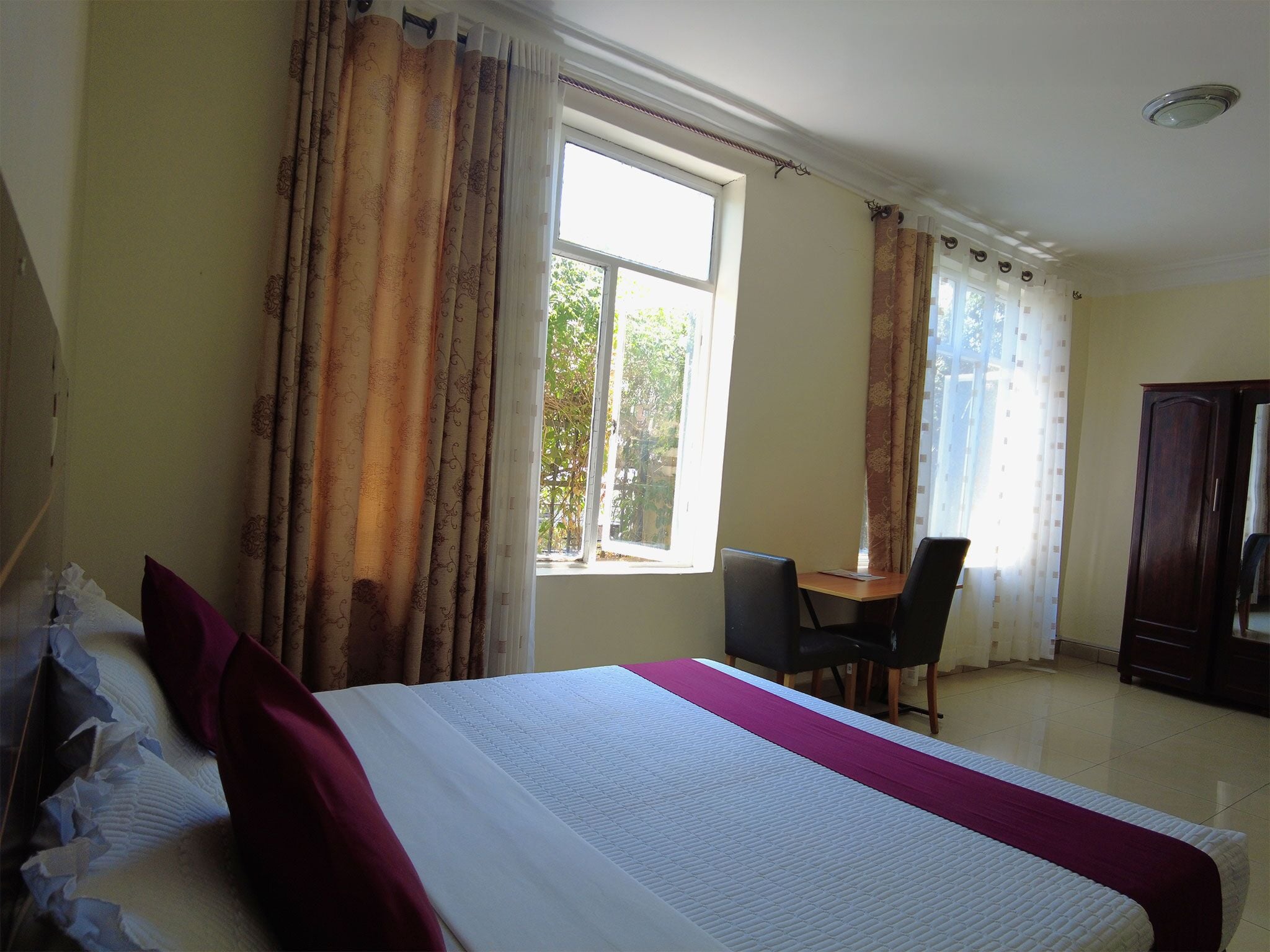 A hotel room with a bed, a desk, and a wardrobe.