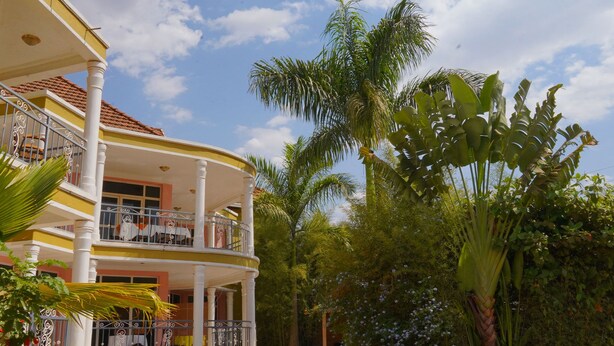 Un edificio de dos pisos con un balcón, rodeado de vegetación tropical.