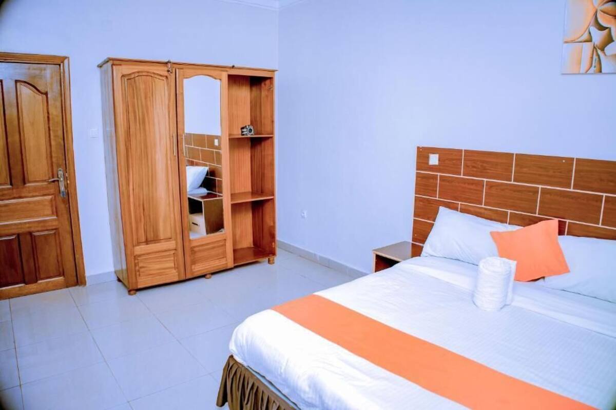A bedroom with a bed, a wardrobe, a nightstand, and a wall art piece.