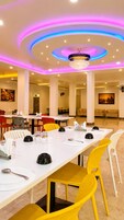 A dining area with a long table, multiple chairs, and a chandelier.