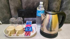 Un plateau avec deux tasses, une bouilloire, une bouteille d’eau et quelques en-cas.