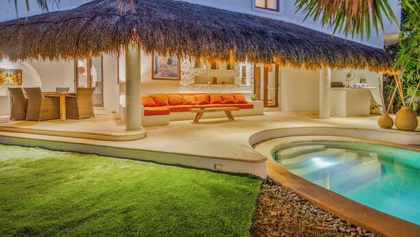 A poolside area with a thatched roof, a sofa, and a dining table. - Beautiful 4-bedroom Villa with Private Pool close to Hotel Zone (Cancún)