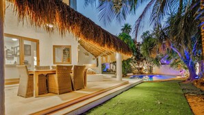 A resort with a thatched-roof outdoor area, a pool, and a well-maintained lawn. - Beautiful 4-bedroom Villa with Private Pool close to Hotel Zone (Cancún)