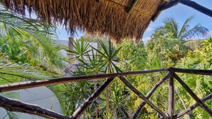 A thatched roof structure, a bamboo fence, and dense tropical foliage. - Beautiful 4-bedroom Villa with Private Pool close to Hotel Zone (Cancún)