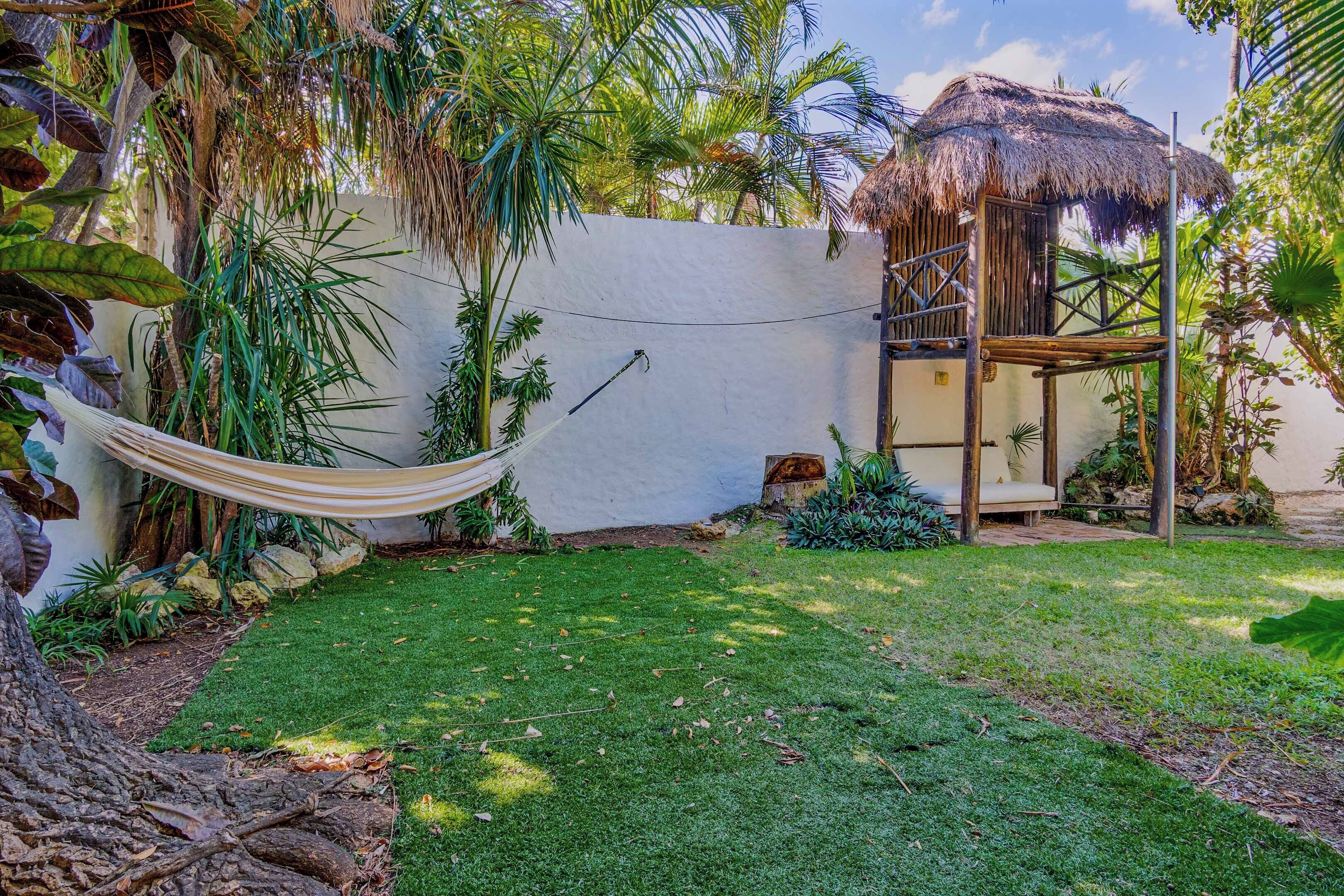A hammock, a thatched-roof structure, and a well-maintained grassy area.