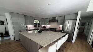Una cocina moderna con una isla grande, electrodomésticos de acero inoxidable y piso de madera.