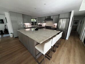 Eine moderne Küche mit einer großen Kochinsel, Edelstahlgeräten und Holzboden.