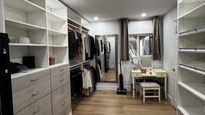 Un vestidor con repisas abiertas, un tocador con espejo y un escritorio con una silla.