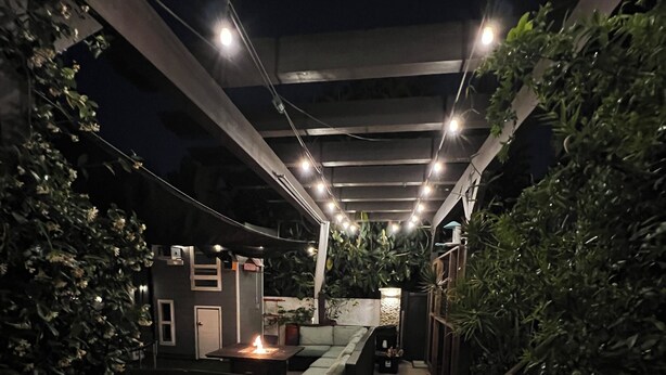 Un patio al aire libre con un conjunto de asientos, una pequeña mesa con una vela y plantas en macetas.