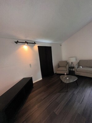 Un salon comprenant un canapé, une table basse, une lampe et un luminaire au plafond.