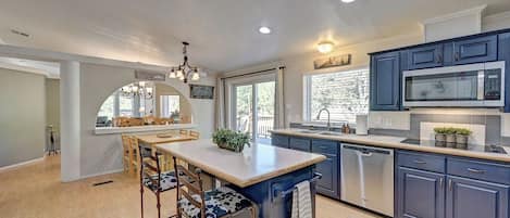 A modern kitchen with a central island, bar stools, and a dishwasher.