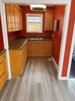 A kitchen with wooden cabinets, a sink, and a window with blinds.