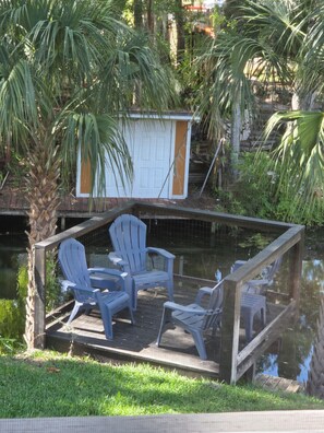 A dock with chairs and a small shed by a body of water, surrounded by greenery. - 3-bedroom house in lovely Chassahowitzka with AC and a range of activities. (Homosassa)