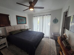 A bedroom with a bed, a nightstand, a ceiling fan, a window with curtains, and a wall-mounted TV. - 3-bedroom house in lovely Chassahowitzka with AC and a range of activities. (Homosassa)