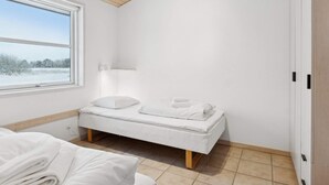 A bedroom with a bed, a window, a bedside table, and a wardrobe. - 4 Star Holiday Home in Pandrup (Pandrup)