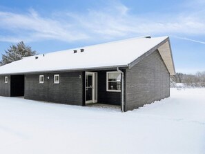 A single-story building with a dark exterior, a sloped roof, and a garage door. - 4 Star Holiday Home in Pandrup (Pandrup)