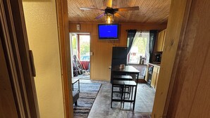 Un interior de madera con ventilador de techo, televisor, comedor y cocina.