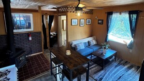 Interior acogedor de una cabaña con techo de madera, una mesa de comedor, un sofá y una chimenea.