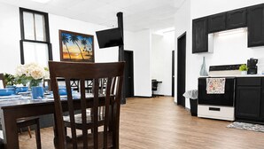 A modern kitchen with black cabinets, a white stove, and a dining area with a wooden table and chairs.