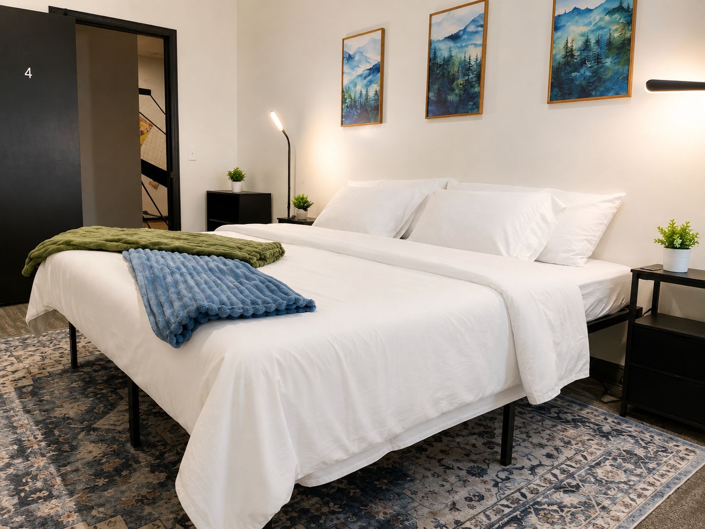 A bedroom with a bed, a nightstand, a lamp, and a door.