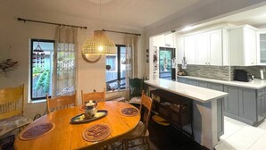 A dining area with a wooden table and chairs, a pendant light, and a view of the kitchen with white cabinets. - 2 Bedroom House in the Heart of Miami + Parking (Miami)