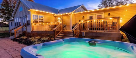 Una casa con idromassaggio, terrazza in legno e luci decorative.