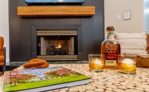 Ein Kamin mit einem Buch mit dem Titel 'Bardstown' und einer Flasche Elijah Craig Whiskey auf einem Tisch.
