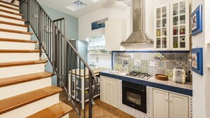 A kitchen with a stove, oven, and cabinets, a staircase with wooden steps, and a ceiling fan. - La Casetta Azzurra (Aci Castello)