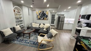 Una sala de estar moderna con un sofá modular, una mesa de centro de vidrio y una mesa de futbolín.