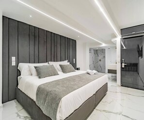 A modern bedroom with a large bed, a dark headboard, and a shower area. - Aman 15br2 Pools Park Lleras Events Ok (Medellín)