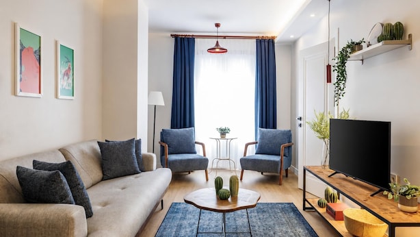 A modern living room with a sofa, two armchairs, a coffee table, a TV, and a wooden side table with plants. - House Sleeps 7 With Air Conditioning (Istanbul)