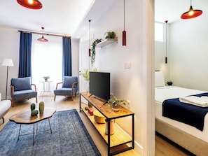 A modern hotel room with a sofa, two armchairs, a TV, a wooden side table, and a bed. - House Sleeps 7 With Air Conditioning (Istanbul)