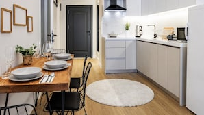 A compact kitchen with white cabinets, a black stove hood, and a dining area with a wooden table and chairs. - House Sleeps 7 With Air Conditioning (Istanbul)