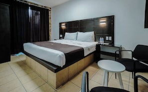 A hotel room with a bed, bedside table, chair, and a small round table. - Hotel las Piedra Stone (Acapulco de Juárez)