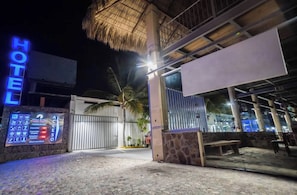 A hotel entrance with a neon sign, a gate, and a palm tree. - Hotel las Piedra Stone (Acapulco)