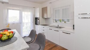 Una cucina moderna con mobili bianchi, forno integrato e una finestra con vista.