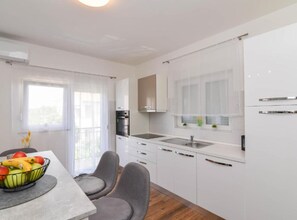 A modern kitchen with white cabinets, a built-in oven, and a window with a view. - One Bedroom Apartment with Terrace and Sea View (Sukosan)